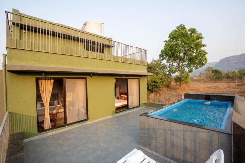 a house with a swimming pool in front of it at Eden Springs by VEO - Part of StayVista in Karjat
