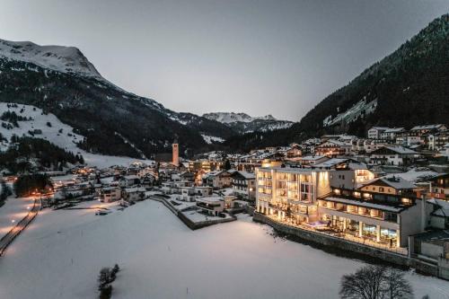 a town in the snow at night with mountains at Seehotel Panorama Relax in Resia