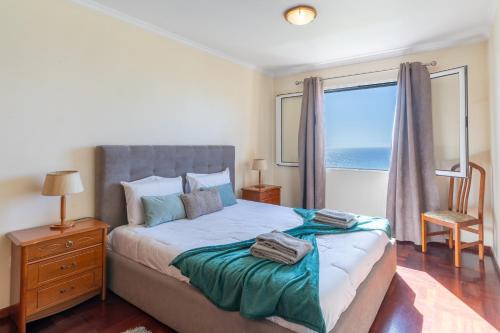 a bedroom with a bed and a window with the ocean at Apartamento Vista Azul in Funchal
