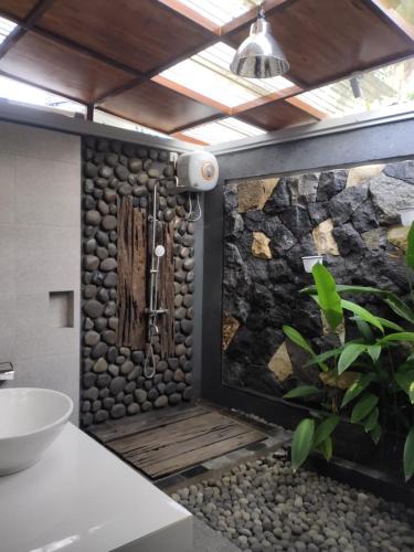 a bathroom with a shower with a stone wall at Shanaya Hotel & Cafe in Borobudur