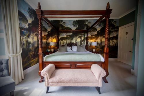 a bedroom with a canopy bed and a chair at Burleigh Court Hotel in Stroud