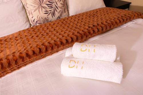 a bed with two towels and two folded towels at Dikalo Highston Boutique Guest house in Bryanston Sandton Johannesburg in Johannesburg