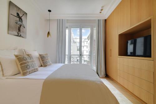 - une chambre avec un lit et une télévision murale dans l'établissement Écrin de Prestige à Dauphine, à Paris