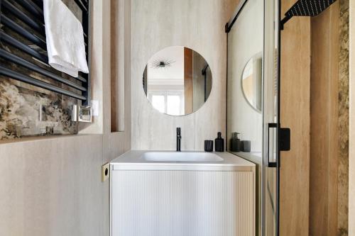 une salle de bain avec un lavabo et un miroir dans l'établissement Écrin de Prestige à Dauphine, à Paris