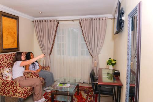 two people sitting on a couch in a living room at Dikalo Highston Boutique Guest house in Bryanston Sandton Johannesburg in Johannesburg