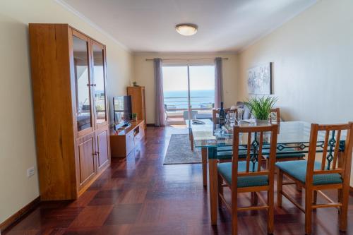 a dining room with a table and chairs and the ocean at Apartamento Vista Azul in Funchal
