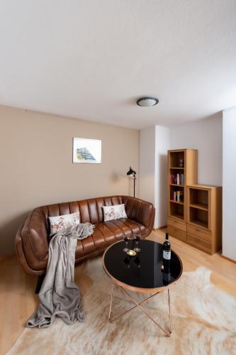 a living room with a brown leather couch and a table at Ferien im Paradies - Wohnung Prima in Höchst