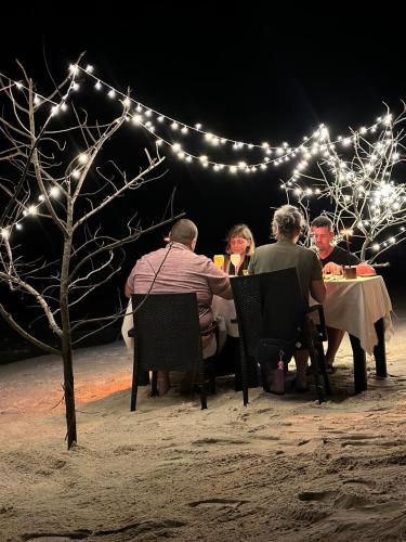a group of people sitting at a table with lights at Nika Inn Himandhoo in Himandhoo 