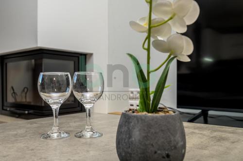 a table with two wine glasses and a vase with flowers at Luxurious Tsimiski 2nd Floor in Alexandroupoli