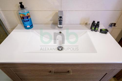 a bathroom sink with a bottle of alcohol on it at Luxurious Tsimiski 2nd Floor in Alexandroupoli
