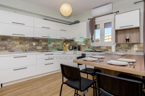 a kitchen with white cabinets and a wooden table at Luxurious Tsimiski 2nd Floor in Alexandroupoli