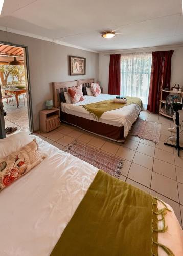 a bedroom with two beds and a large window at Die Woestynroos Gastehuis in Isidule