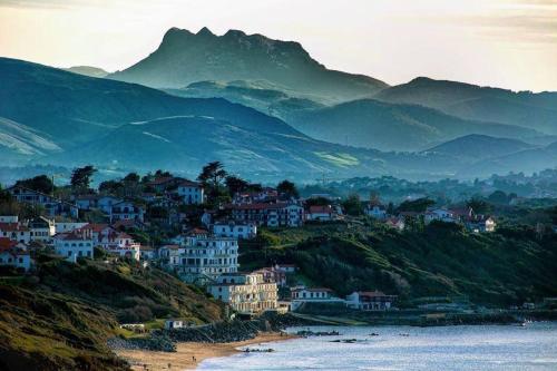 a town on a hill with mountains in the background at Pinpirinia min 3 nuits in Guéthary