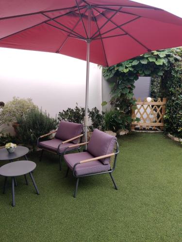 a patio with two chairs and a red umbrella at Pinpirinia min 3 nuits in Guéthary