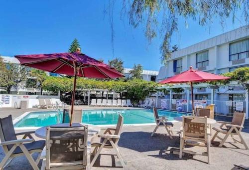 una piscina con sedie e ombrelloni di fronte a un hotel di Motel 6-Belmont, CA - San Francisco - Redwood City a Belmont
