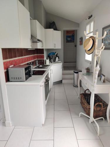 a white kitchen with white cabinets and a microwave at Pinpirinia min 3 nuits in Guéthary