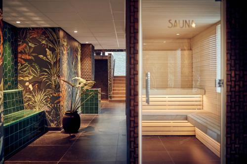 a bathroom with a sauna and a vase with flowers at Van der Valk Hotel Amsterdam - Amstel in Amsterdam