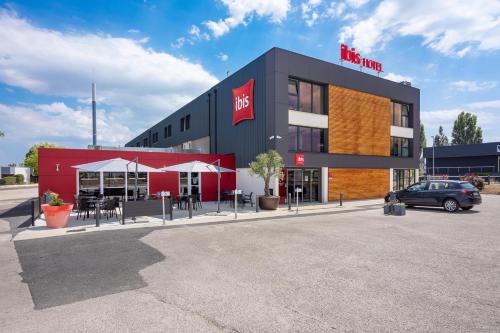 a building with a car parked in a parking lot at ibis Dijon Sud in Perrigny-lès-Dijon