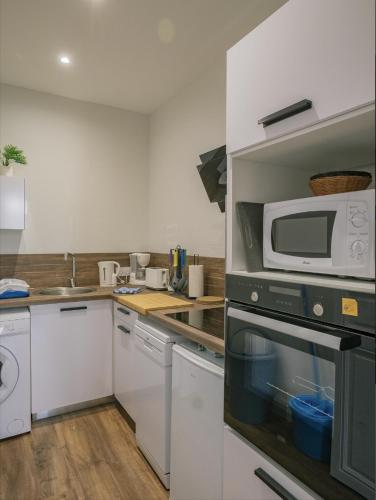 une cuisine avec un micro-ondes et une cuisinière dans l'établissement Appartement refait à neuf avec cachet de l'ancien, à Saumur