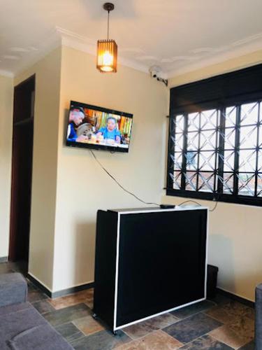 a living room with a tv on the wall at SONKOYAZ BED AND BREAKFAST Near UN BASE in Entebbe