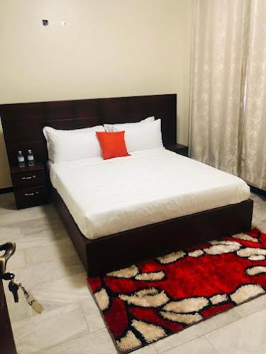 a bedroom with a bed with a red pillow and a rug at SONKOYAZ BED AND BREAKFAST Near UN BASE in Entebbe