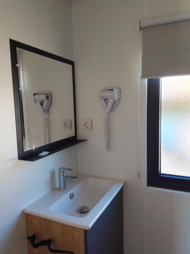 une salle de bain avec un lavabo et un miroir dans l'établissement Camping les lodges du lagon, à Calvisson