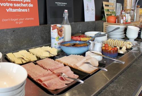 a counter with cheese and meats and other food items at ibis Dijon Sud in Perrigny-lès-Dijon