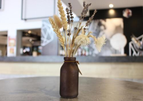 a brown vase with flowers in it on a table at ibis Dijon Sud in Perrigny-lès-Dijon