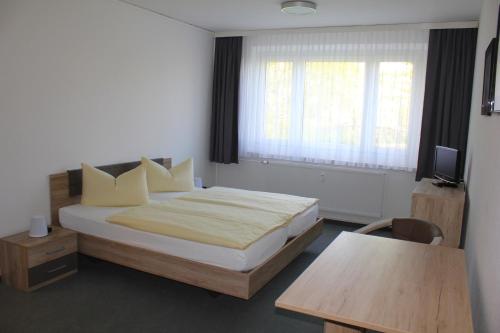 a bedroom with a bed and a table and a window at Vario Gästehaus in Greifswald