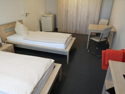 a room with two beds and a table and a desk at Vario Gästehaus in Greifswald