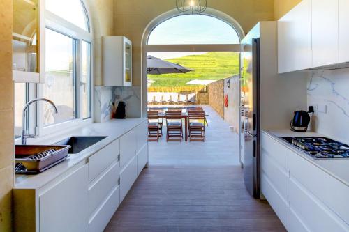 a kitchen with white cabinets and a dining room with a table at Solaris Holiday Home in Għasri