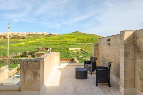 a balcony with two chairs and a view of a hill at Solaris Holiday Home in Għasri