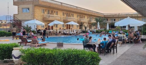 a group of people sitting around a swimming pool at Ciao Hotel in Nuweiba
