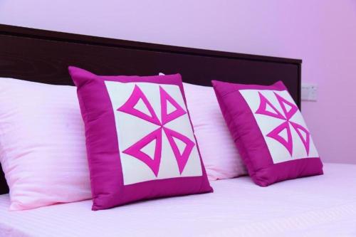 a bed with pink and white pillows on it at Airport Blessings Villa in Katunayake