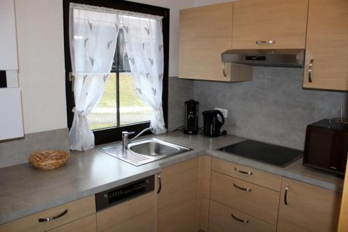 une cuisine avec un évier et une fenêtre dans l'établissement Ferienhaus Nr 42, Kategorie Komfort, Feriendorf Hochbergle, Allgäu, à Lechbruck am See