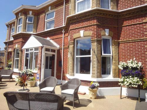 a brick building with chairs and flowers in front of it at Brooke House in Shanklin