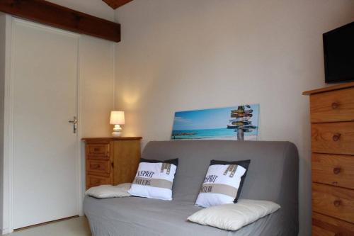 Un dormitorio con un sofá gris con dos almohadas. en Appartement 2 pièces 4 couchages Dolus d'Oléron DDO000-008, en Dolus d'Oléron