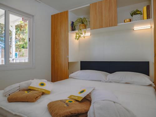 a bedroom with a bed with towels and a window at Club del Sole Due Laghi Levico Family Collection in Levico Terme