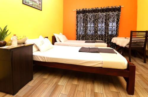 two beds in a room with orange and yellow walls at Namasthe Ayurveda and Yoga Retreat Cochin in Nedumbassery