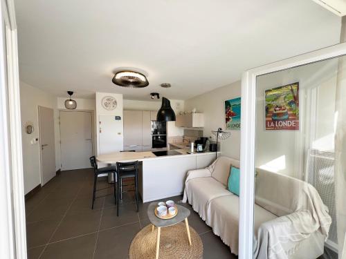 un salon et une cuisine avec un canapé et une table dans l'établissement Très bel appartement pour 3 avec piscine à Chateau Vert, à La Londe-les-Maures