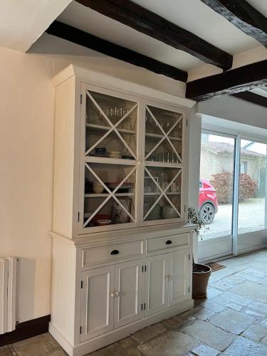 a large white cabinet with glass doors in a room at Maison Terracotta, le calme aux portes de Poitiers in Saint-Julien-lʼArs