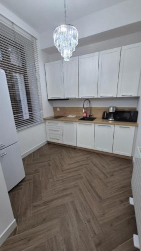 a kitchen with white cabinets and a wooden floor at APARTAMENT JARACZA 28 nr 4 in Słupsk