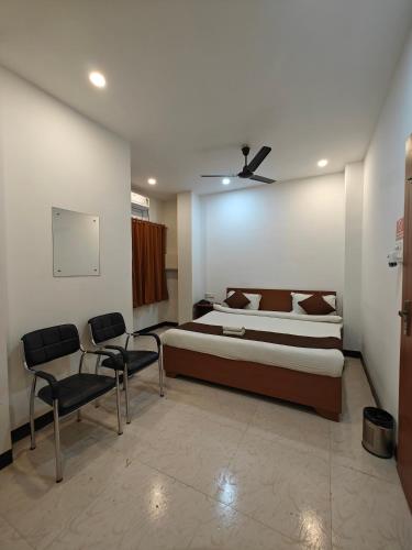 a bedroom with a bed and chairs in it at Hotel New Ganga in Guwahati
