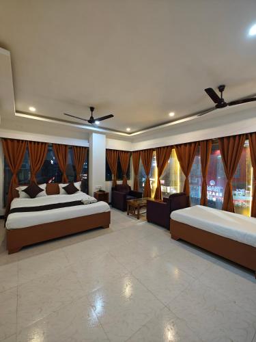a bedroom with two beds and a large window at Hotel New Ganga in Guwahati
