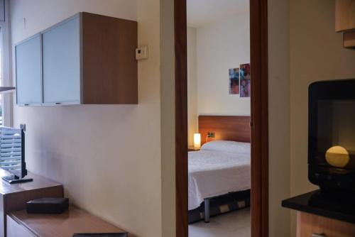 a small bedroom with a bed and a television at Beachfront Apartment with Pool and Garden S Abanell Blanes in Blanes
