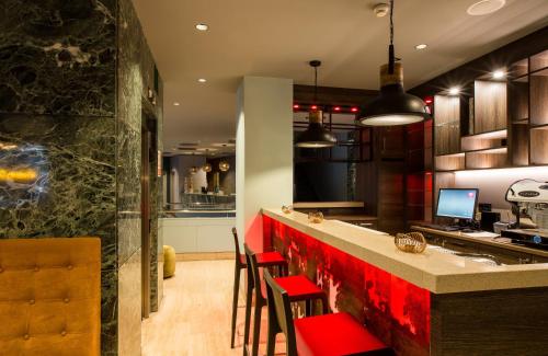 a kitchen with a red counter and some chairs at Leonardo Boutique Hotel Madrid in Madrid