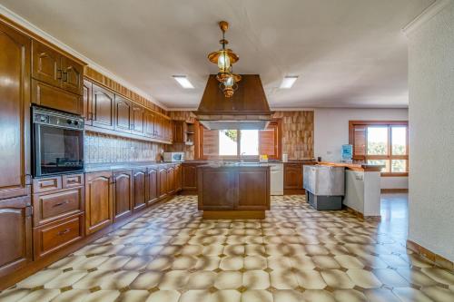 a large kitchen with wooden cabinets and a chandelier at Villa Montgrau in Llano de Gorra