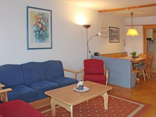 - un salon avec un canapé bleu et des fauteuils rouges dans l'établissement Ferienhaus Nr 46, Kategorie Komfort L, Feriendorf Hochbergle, Allgäu, à Lechbruck am See