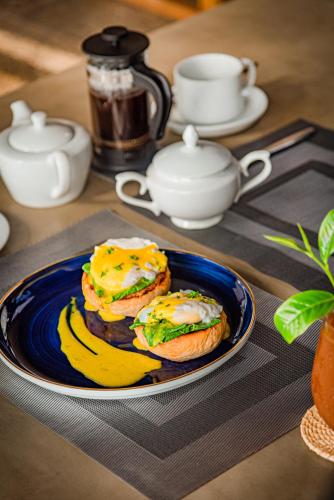 twee ontbijtsandwiches op een blauw bord op een tafel bij The Coast Sri Lanka, Bentota in Bentota