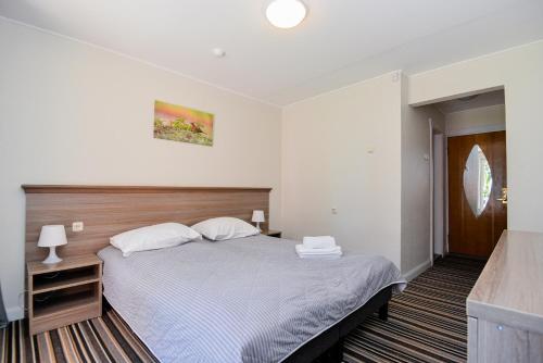 a bedroom with a large bed and a television at Skalva Nida in Nida